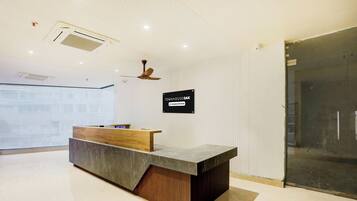 A reception desk with a sign indicating 'Company-Served' services, a ceiling fan, and a glass door leading to an interior space.