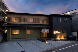 En tvåvåningsbyggnad med en traditionell japansk entré och en modern tillbyggnad.