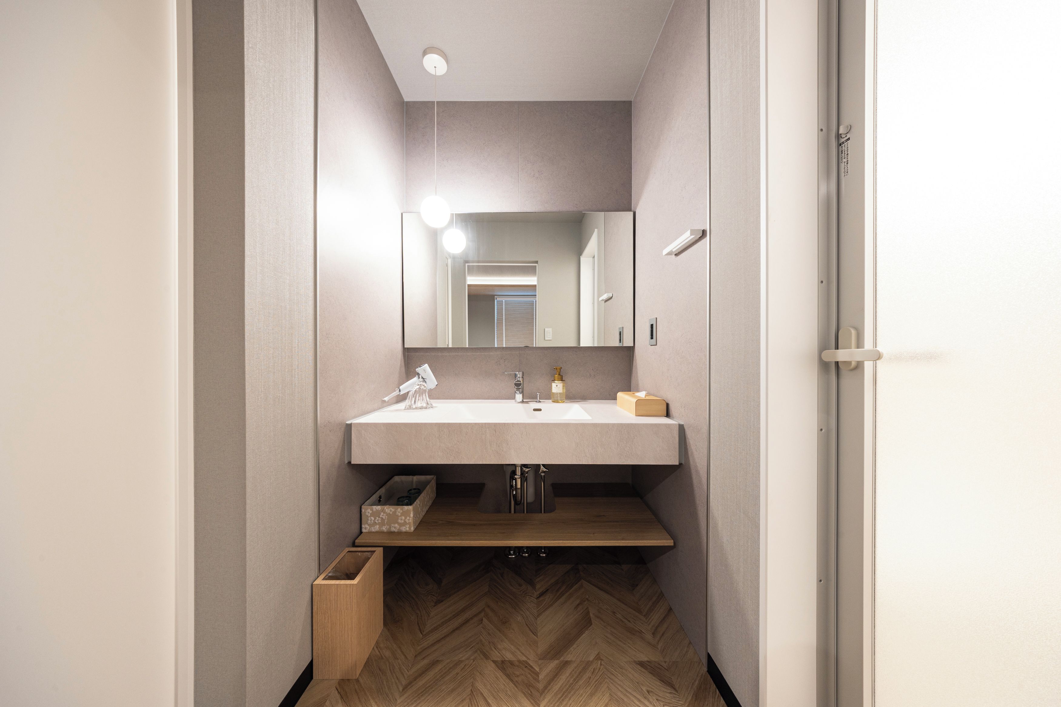 Een moderne badkamer met een grote spiegel, een wastafel en een houten vloer.