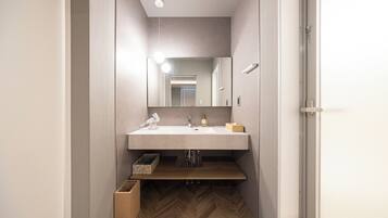 Een moderne badkamer met een grote spiegel, een wastafel en een houten vloer.
