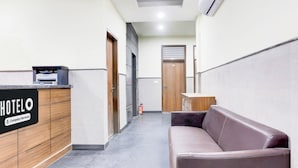Un'area della reception di un hotel con una scrivania, un divano e un estintore.