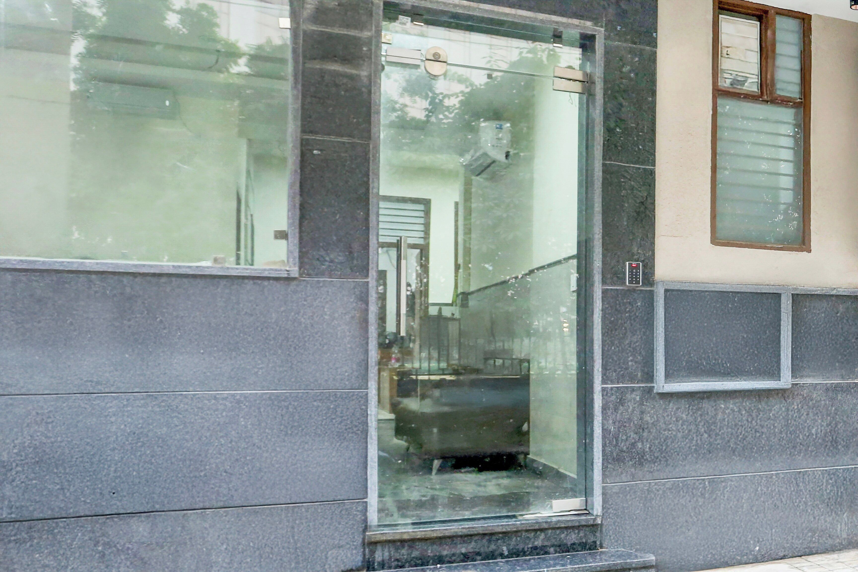 A building entrance with a glass door, a small step leading up to it, and a window to the right.