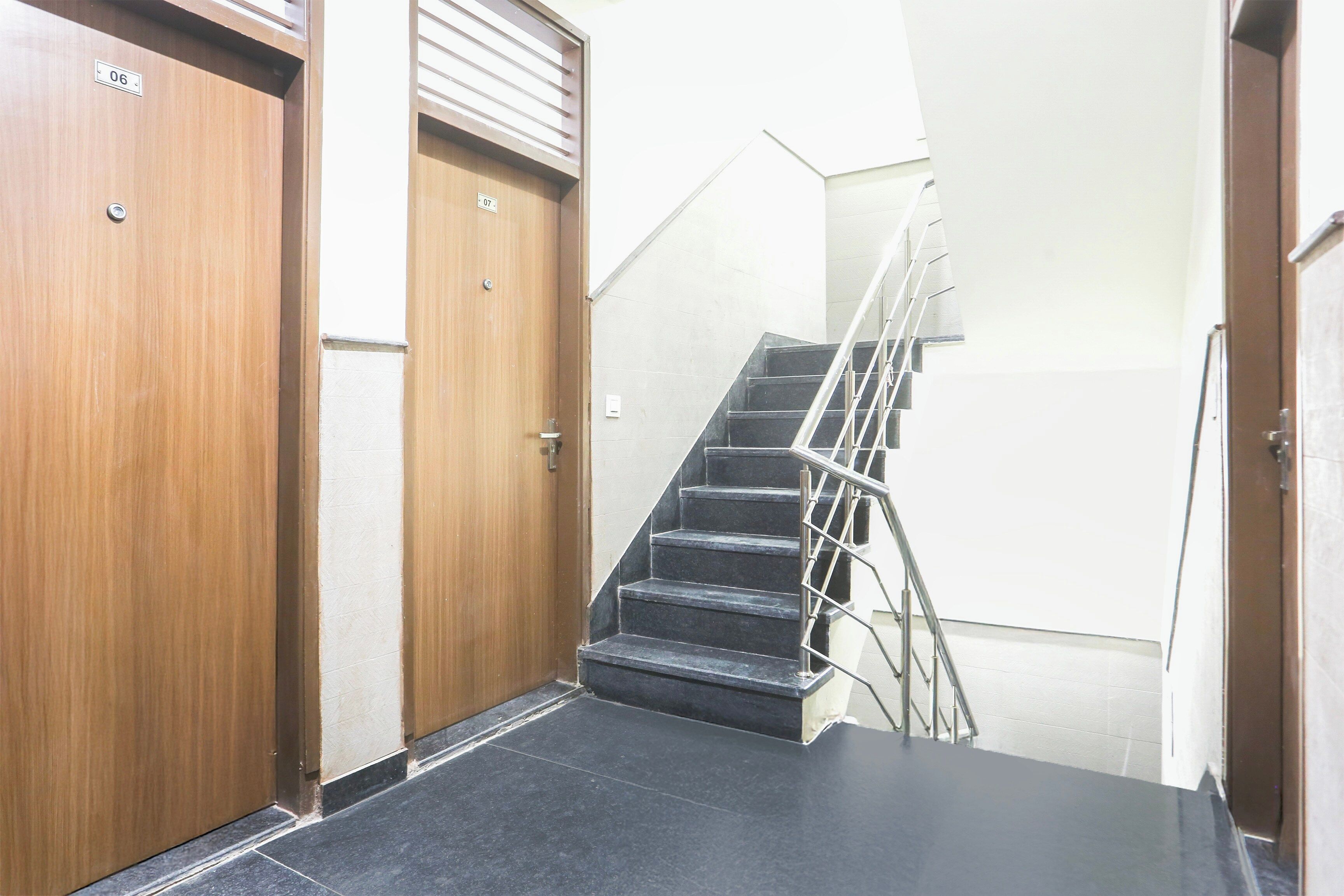A hallway with two wooden doors, one marked with the number 06 and the other with 07, leading to a staircase with metal railings.