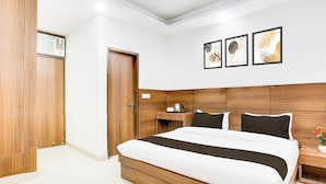 Camera d'albergo con un letto grande, una testiera in legno, comodini, un armadio e tre quadri appesi al muro.