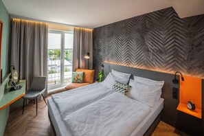 Ein modernes Hotelzimmer mit einem großen Bett, einem Schreibtisch und einem Sessel.