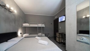 A hotel room with a bunk bed, a desk, a chair, a television, and a mirror. - Il Taschino Suite (Naples)