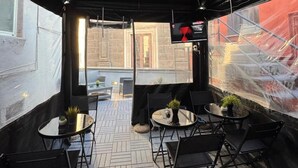 An outdoor patio with a black umbrella, tables, chairs, and potted plants. - Il Taschino Suite (Naples)