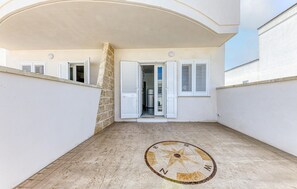 A covered outdoor area with a stone wall, a door leading to a kitchen, and a compass floor design. - 1 bedroom stunning home in Torre San Giovanni (Torre San Giovanni)
