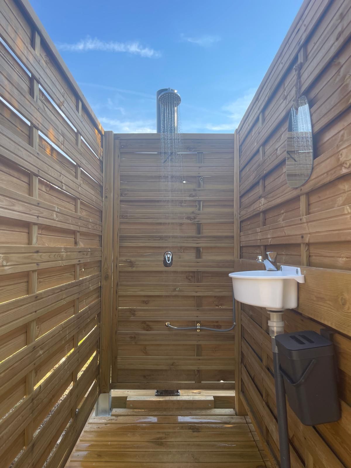 Un sauna en bois avec un banc, un lavabo et un miroir.