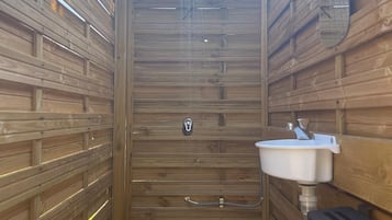 Un sauna en bois avec un banc, un lavabo et un miroir.