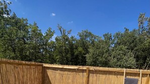 An outdoor hot tub surrounded by a wooden fence with a clear blue sky above.