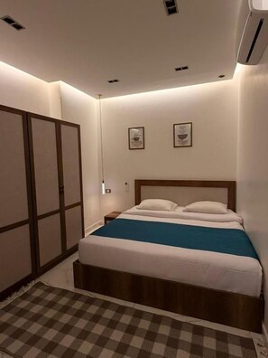 Ein Schlafzimmer mit einem Bett, einem Schachbrettmuster-Teppich, einer Wand-Klimaanlage und einem Holzschrank.