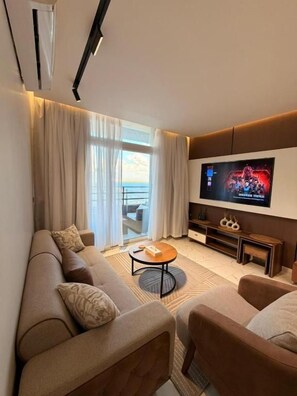 Ein modernes Wohnzimmer mit einer Sofagarnitur, einem Couchtisch und einem an der Wand befestigten Flachbildfernseher.