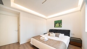 A modern bedroom with a large bed, a headboard, a bedside table, and a painting on the wall. - Tonight Homestay West Nanjing Road Shanghai Taigu Building (Shanghai)