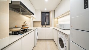 A modern kitchen with a stove, microwave, washing machine, and a window. - Tonight Homestay West Nanjing Road Shanghai Taigu Building (Shanghai)