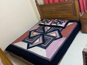 Cama com colcha e travesseiros estampados com padrão geométrico.