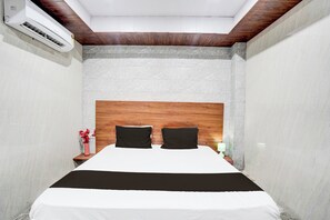 Un dormitorio con una cama, una mesita de noche, una lámpara y un aire acondicionado instalado en la pared.