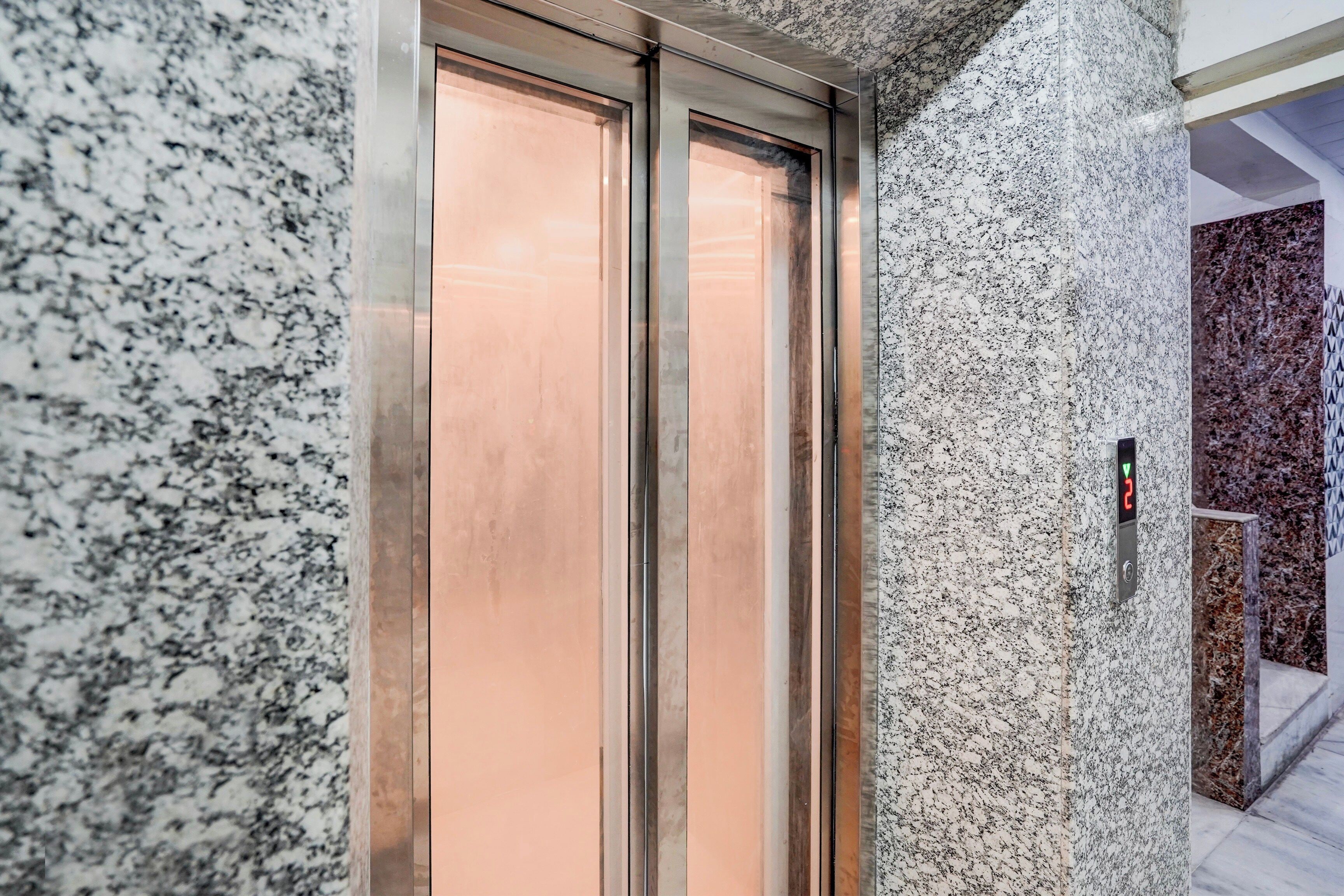 Un ascensor moderno con detalles metálicos y un panel de control con flechas direccionales.