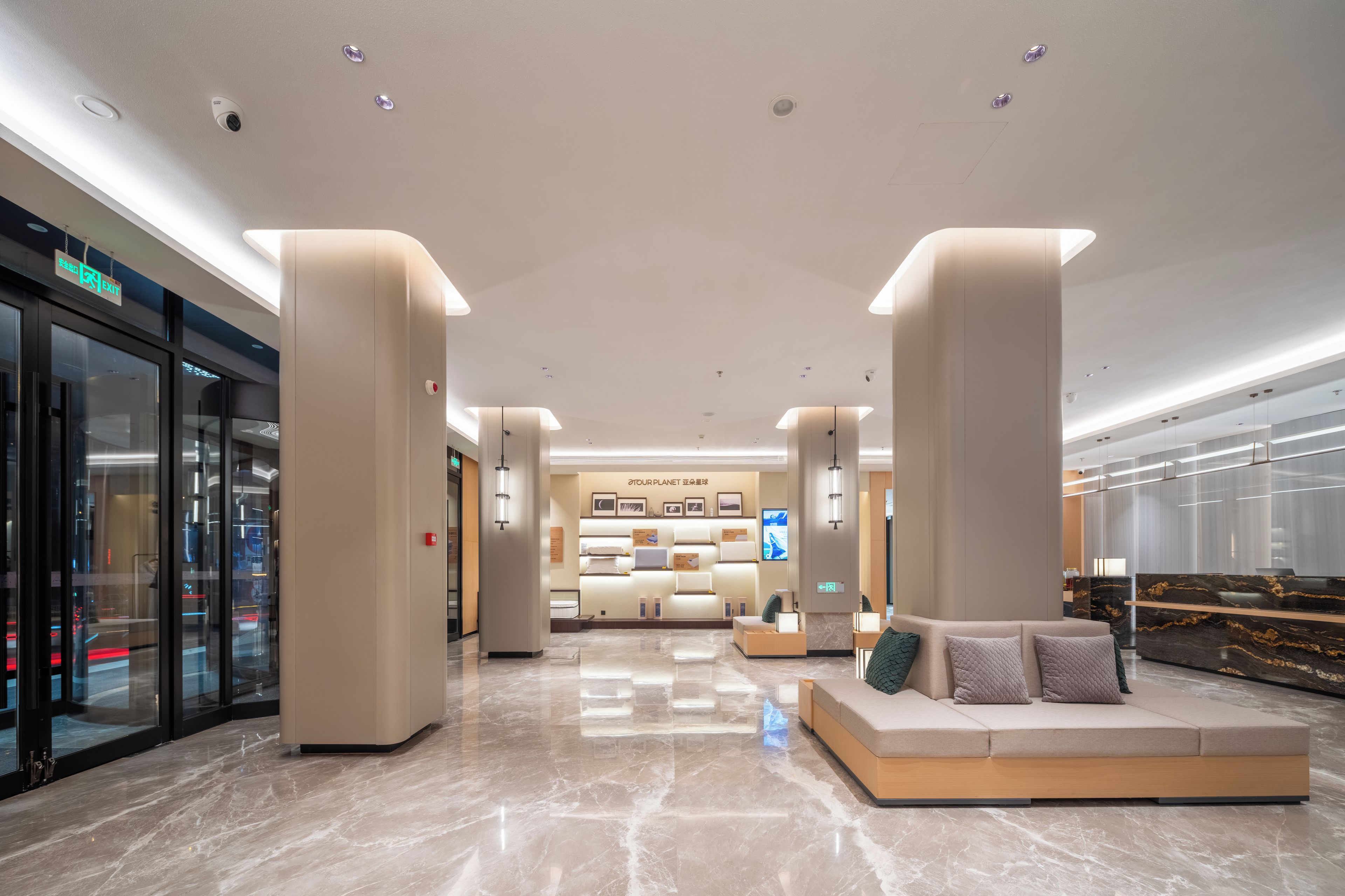 A modern hotel lobby with a reception desk, seating area, and a view of the cityscape through large windows.