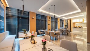 Un moderno vestíbulo de hotel con una zona de estar, una recepción y vistas al área de la cocina.