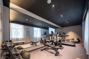 Un gimnasio moderno con diversos equipos de ejercicio, como cintas de correr, bicicletas estáticas y pesas libres.