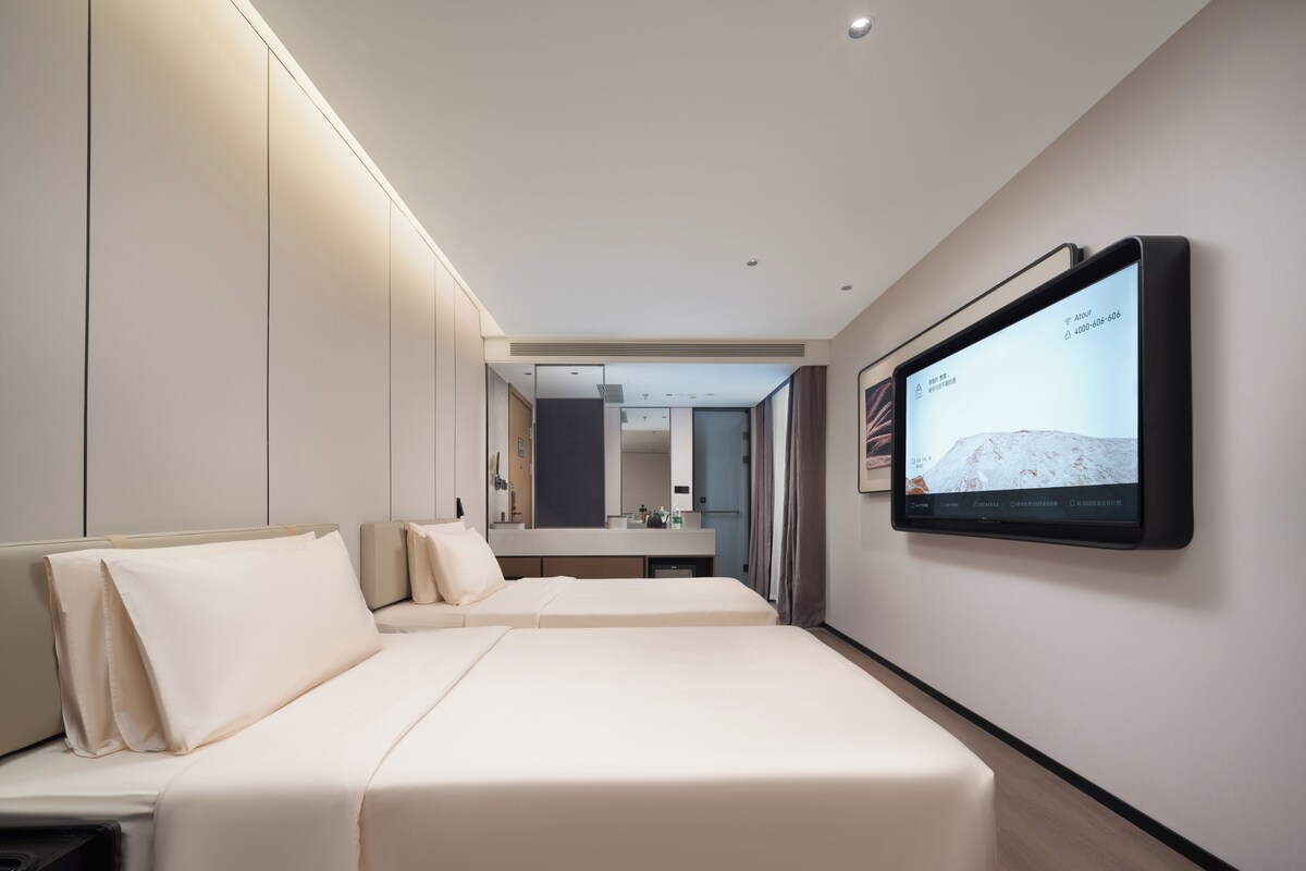 Quarto de hotel moderno com uma grande TV de tela plana na parede, uma cama com cabeceira e uma mesa de cabeceira.