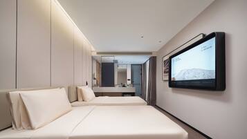 Een moderne hotelkamer met een grote flatscreen televisie aan de muur, een bed met hoofdeinde en een nachtkastje.