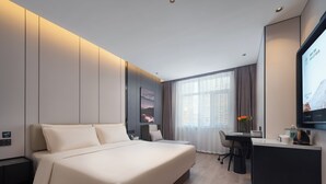 Una habitación de hotel moderna con una cama grande, un escritorio y una televisión.