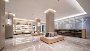 Un moderno vestíbulo de hotel con mostrador de recepción, zona de estar y exhibición de servicios.