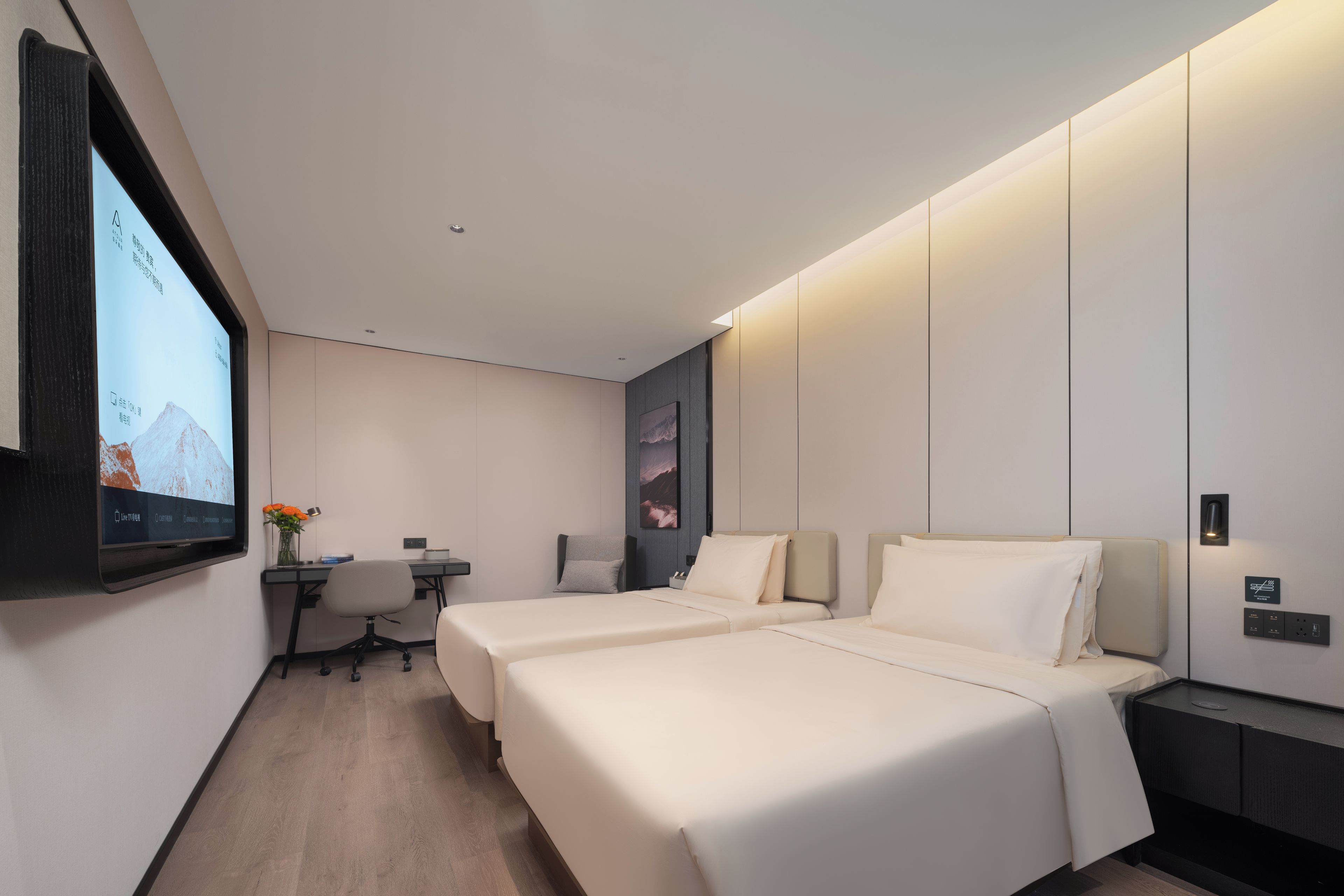 Una habitación de hotel moderna con dos camas, un escritorio y un televisor de pared.