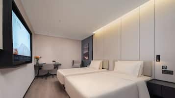 Una habitación de hotel moderna con dos camas, un escritorio y un televisor de pared.