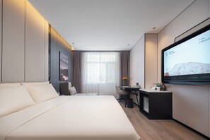 Una habitación de hotel moderna con cama, escritorio, silla, televisor y ventana con cortinas.