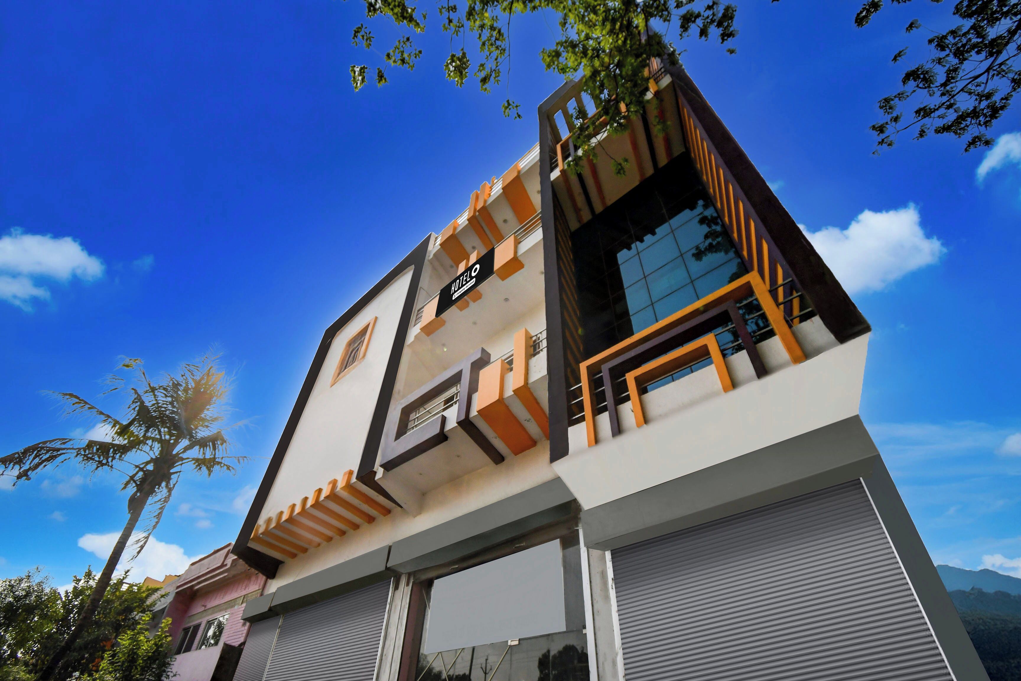 Een modern hotel met een opvallend bord, een balkon en uitzicht op de lucht.