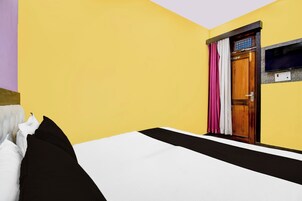 Una habitación de hotel con una cama, una puerta de madera y un televisor fijado a la pared.