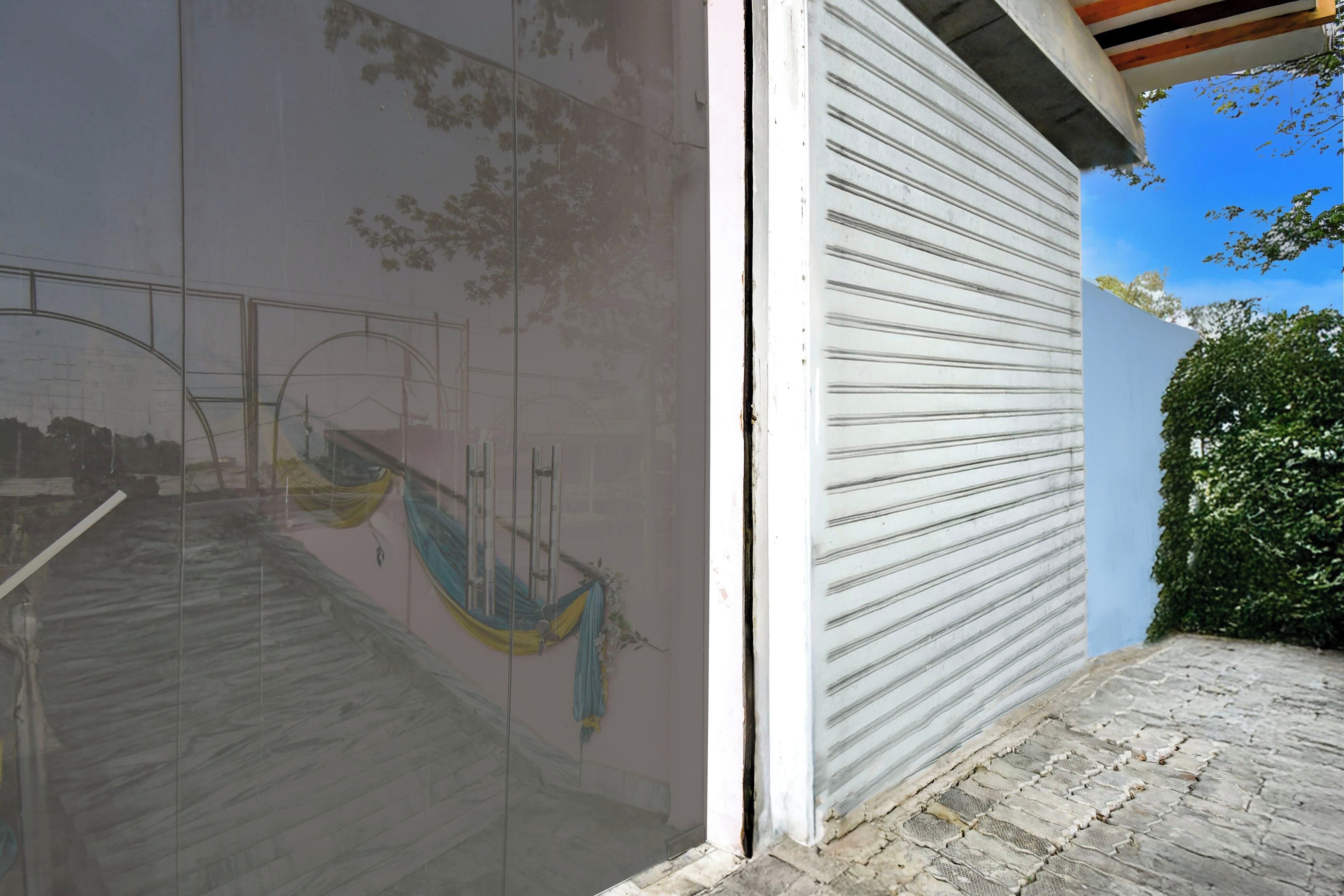 A building exterior with a closed garage door, a clear sky, and a tree.