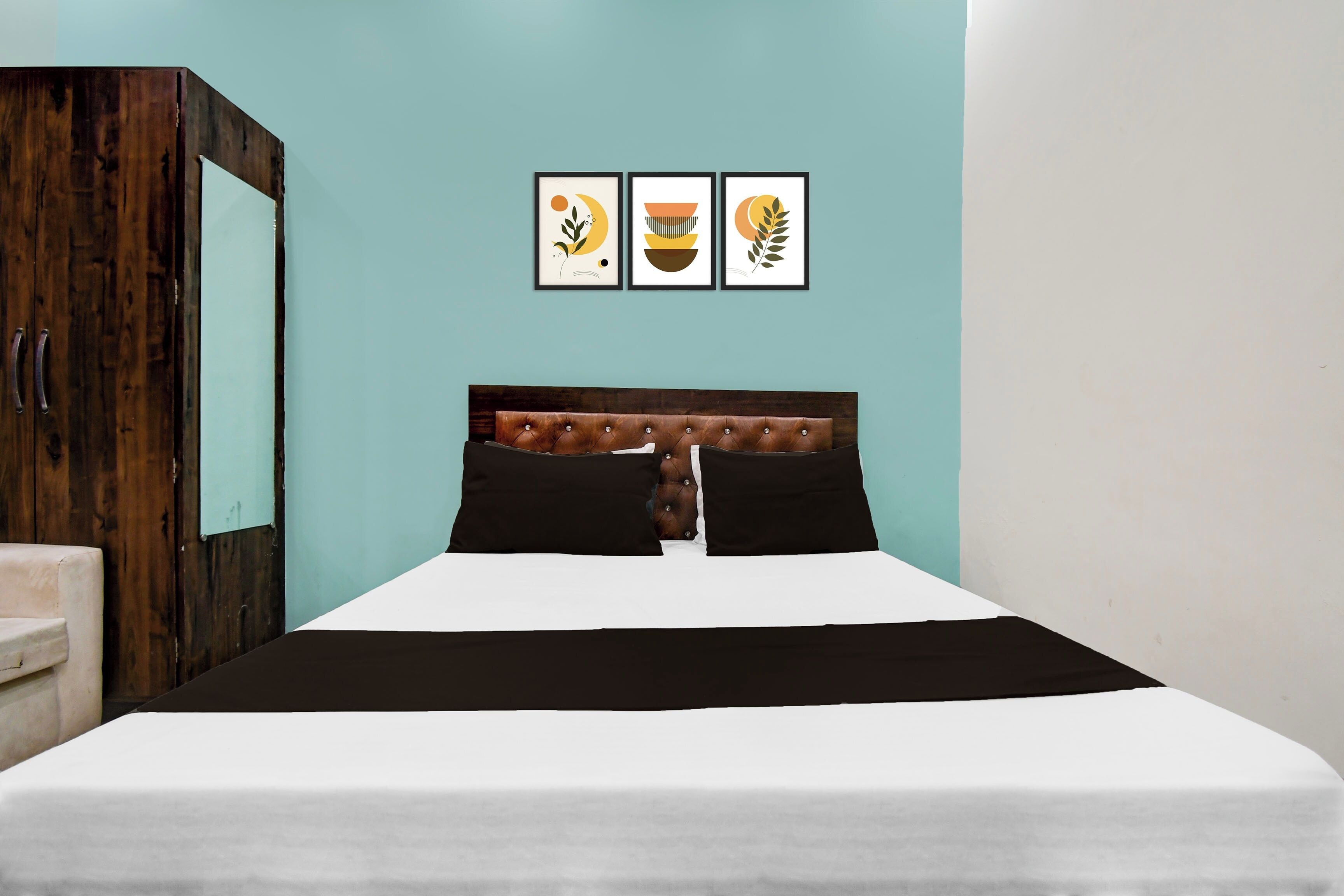 A bedroom with a bed, a wardrobe, and three framed pictures on the wall.