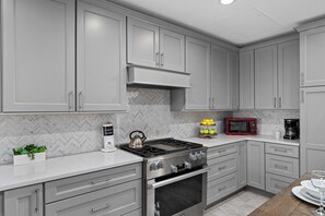 A modern kitchen with grey cabinets, a stainless steel stove, and a herringbone-patterned backsplash. - Reunion Resort Retreat with Game Room & Golf Views (Kissimmee)
