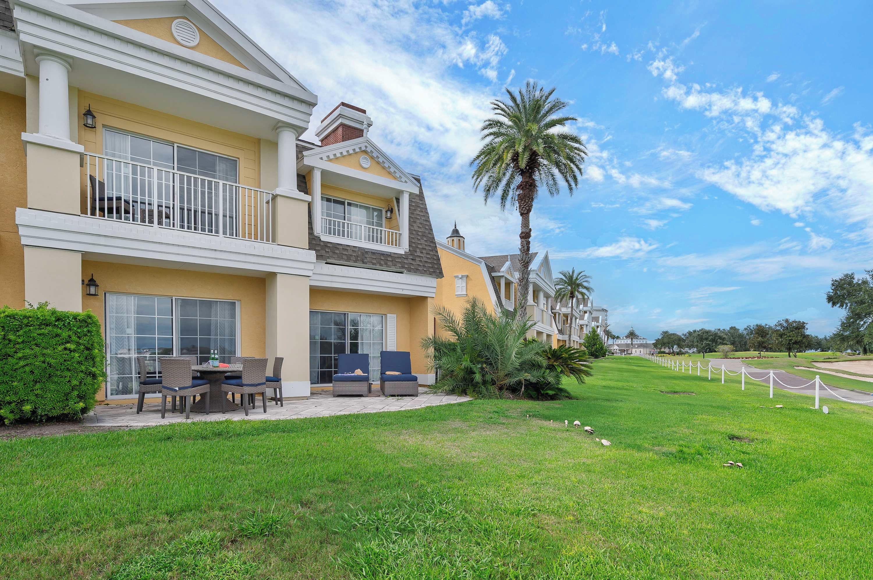 A multi-story hotel with a balcony, outdoor seating, and a well-maintained lawn.