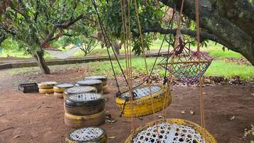 Outdoor swings made from tires under a tree.