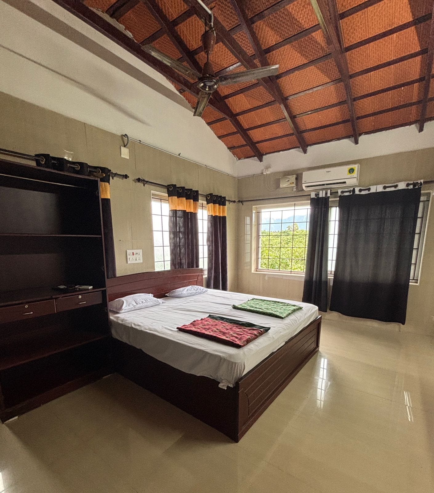 Un dormitorio con cama, armario, ventilador de techo y ventana con cortinas.