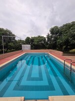 Una piscina rectangular con suelo de baldosas y borde de ladrillo.