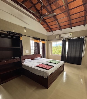 A bedroom with a bed, a wardrobe, a ceiling fan, and a window with curtains.