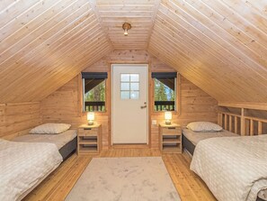 Acogedor dormitorio en ático con dos camas, una puerta con ventana y una mesita con lámpara.