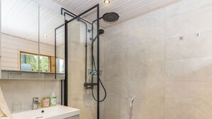 A modern bathroom with a glass shower enclosure, a white sink, and a mirror. - Tykkytie cottage by Interhome (Posio)