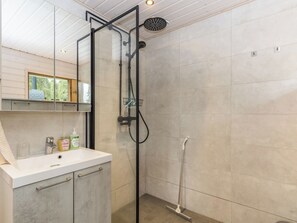 Un baño moderno con cabina de ducha de vidrio, un lavabo blanco y un espejo.