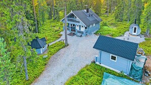 A two-story house with a porch, surrounded by a forested area. - Tykkytie cottage by Interhome (Posio)