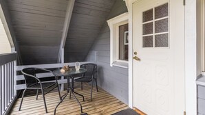 A covered porch with a table and chairs, a white door with a window, and a wooden floor. - Tykkytie cottage by Interhome (Posio)