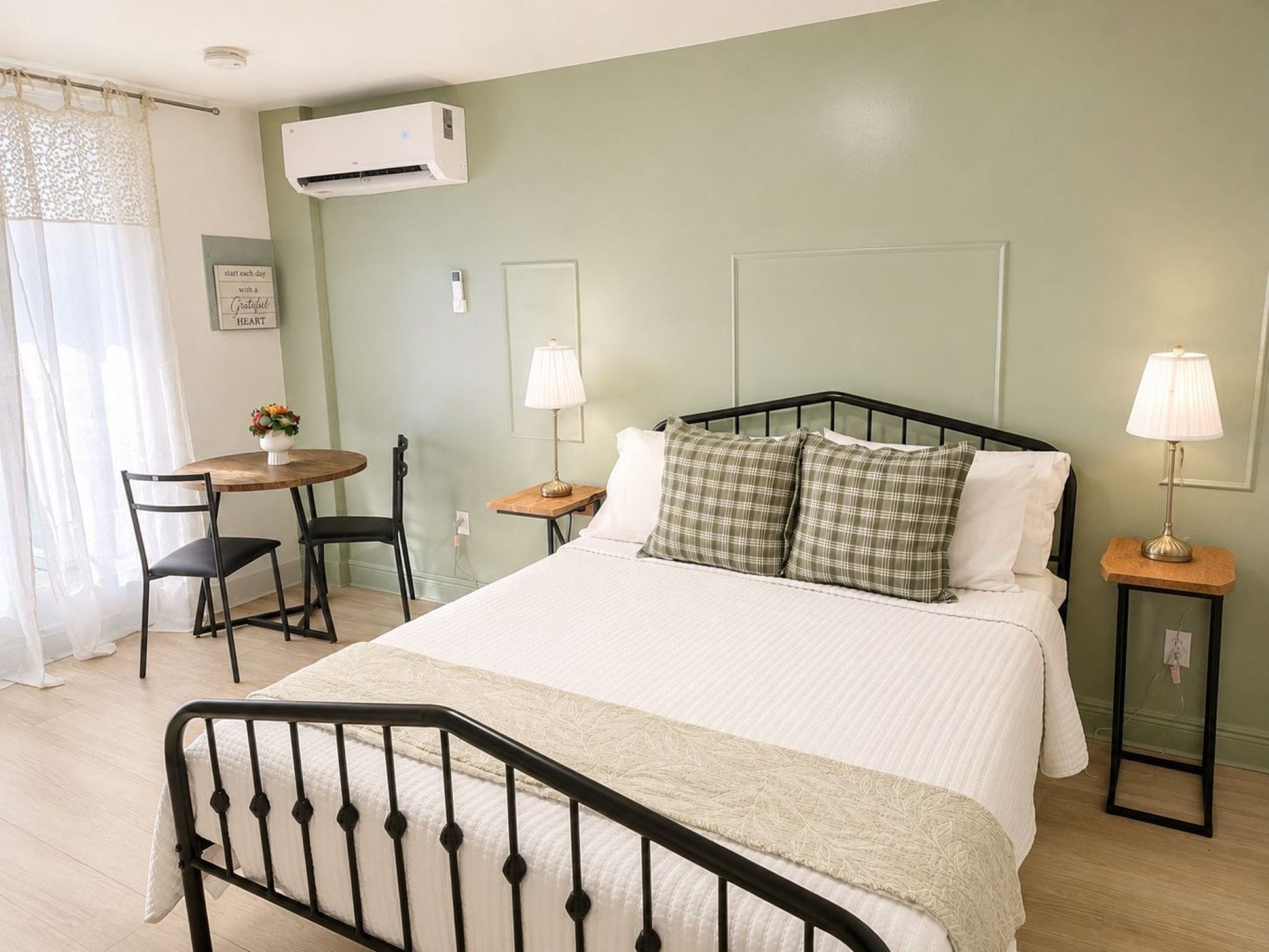 A bedroom with a bed, bedside tables, a desk, and chairs.