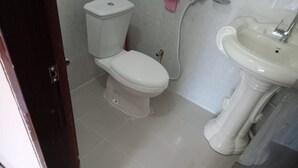 Une salle de bain comprenant des toilettes, un lavabo et une porte donnant sur une autre pièce.