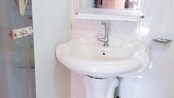 Et badeværelse med en hvid vask, et spejl over vasken og et toilet i hjørnet.